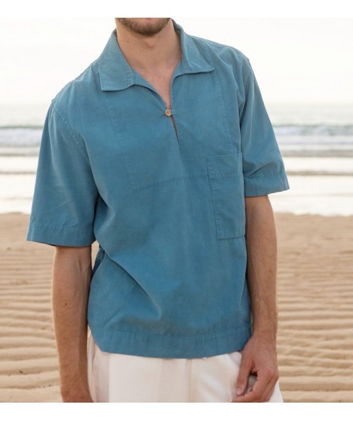 homme sur une plage portant une vareuse bleue et un short blanc