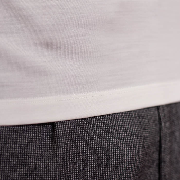 Tee-shirt blanc en laine mérinos et pantalon gris à micro motifs.