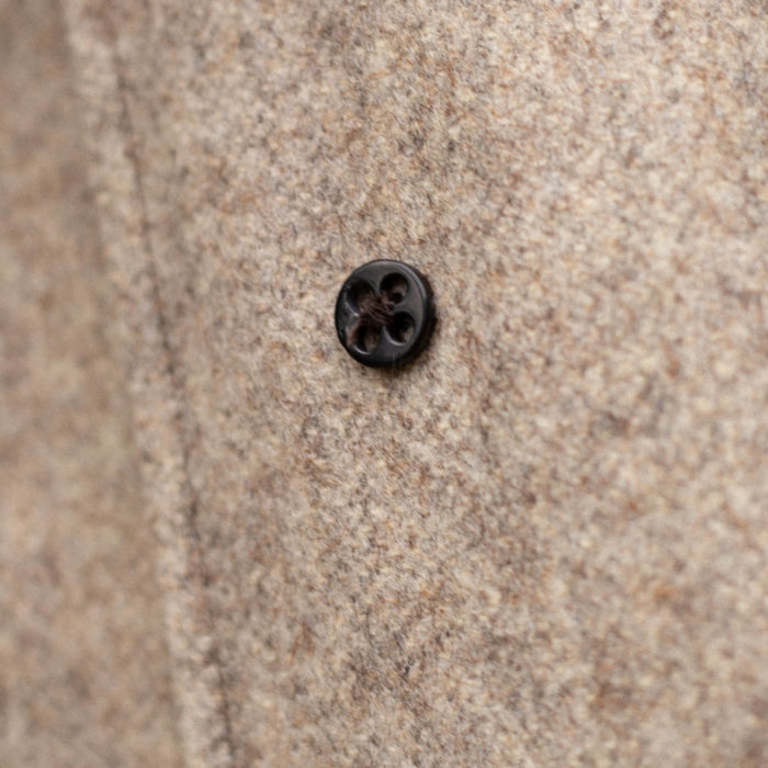 Contre-bouton noir sur drap de laine beige