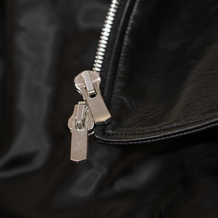 Zip en métal argenté sur cuir noir.