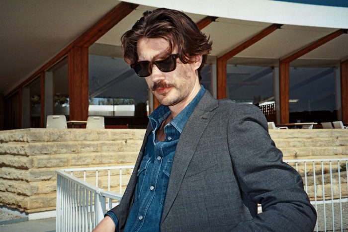 Homme en lunettes de soleil, chemise indigo et blazer gris.